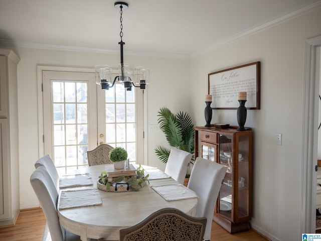 dining area featuring light wood-style floors, a chandelier, and ornamental molding