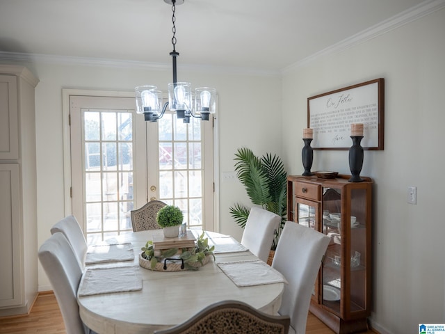 dining space with ornamental molding, light wood-type flooring, and an inviting chandelier