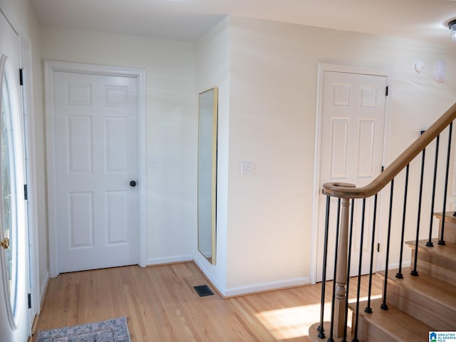 foyer with light wood-type flooring, visible vents, stairway, and baseboards