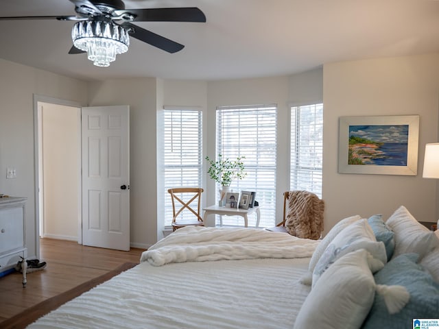 bedroom with ceiling fan, light wood-style flooring, and baseboards