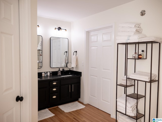 bathroom with double vanity, a sink, and wood finished floors