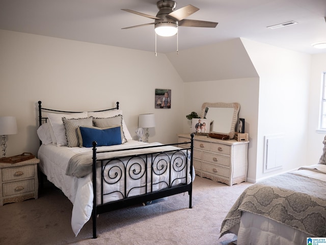 bedroom featuring light carpet, lofted ceiling, visible vents, and a ceiling fan