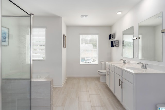 bathroom with a sink, a shower with shower door, toilet, and double vanity