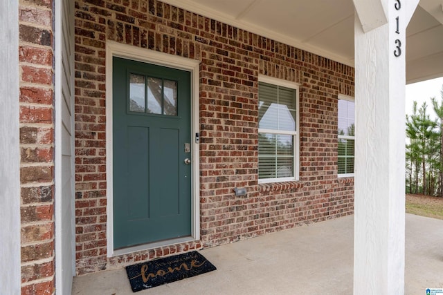 doorway to property with brick siding and covered porch