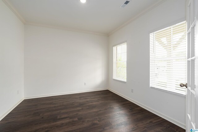 spare room featuring visible vents, baseboards, dark wood-type flooring, and ornamental molding