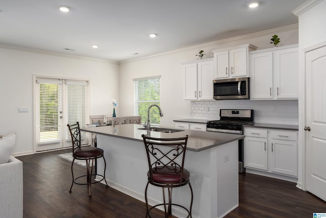 kitchen featuring dark wood-style floors, an island with sink, a sink, appliances with stainless steel finishes, and a kitchen bar