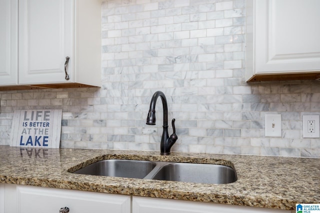 kitchen with tasteful backsplash, white cabinetry, and a sink