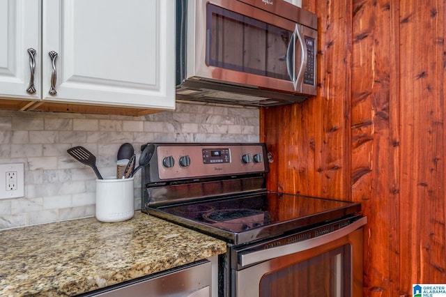 kitchen with stainless steel appliances, white cabinetry, light stone counters, and decorative backsplash