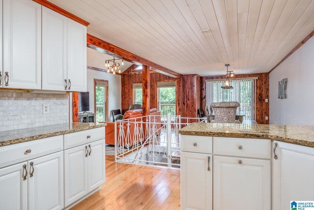 kitchen with a healthy amount of sunlight, light wood finished floors, tasteful backsplash, and decorative light fixtures