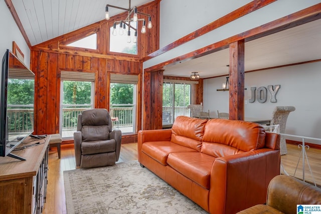 living room with a chandelier, vaulted ceiling, wood walls, and wood finished floors