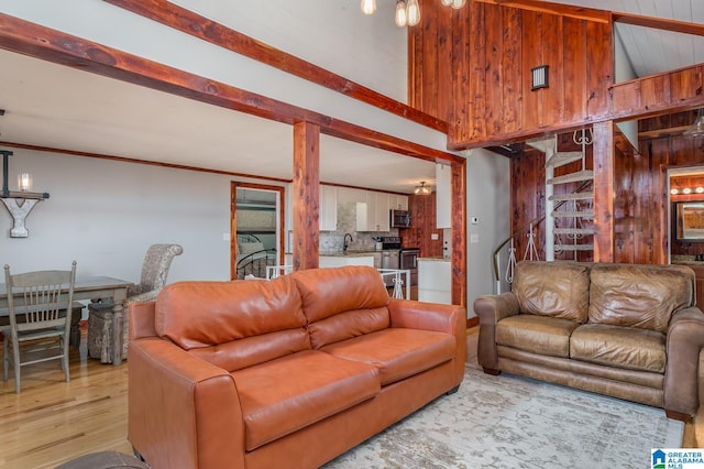 living room with ornamental molding, light wood finished floors, and beam ceiling