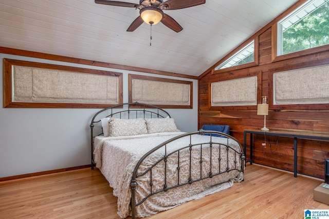 bedroom featuring vaulted ceiling, wood walls, baseboards, and wood finished floors