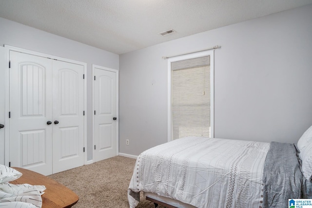 bedroom with baseboards, visible vents, a textured ceiling, carpet floors, and a closet