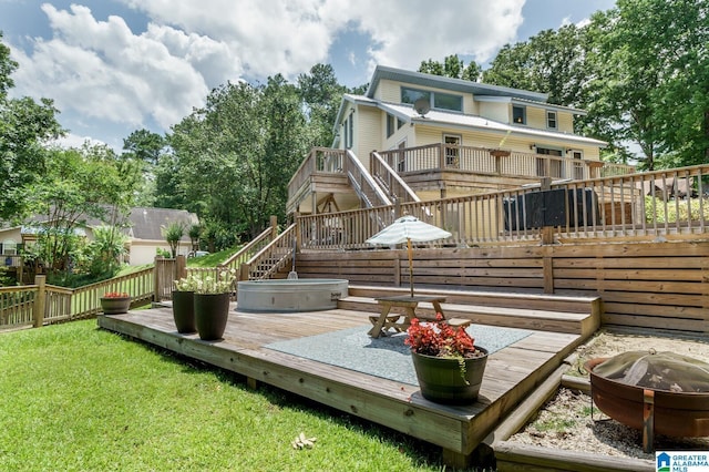 back of house featuring a fire pit, a lawn, a wooden deck, and stairs