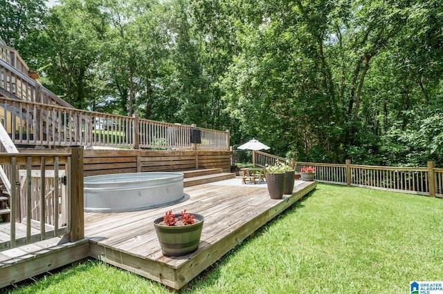 deck featuring a jacuzzi and a lawn