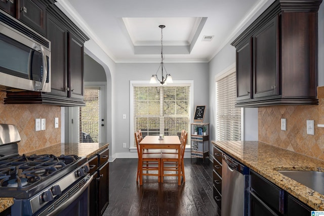 kitchen with visible vents, a tray ceiling, dark wood-style floors, stainless steel appliances, and arched walkways