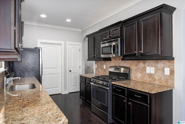 kitchen featuring light stone countertops, dark wood finished floors, a sink, ornamental molding, and stainless steel appliances