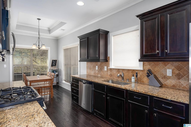 kitchen with a tray ceiling, ornamental molding, stainless steel dishwasher, dark wood-style floors, and a sink