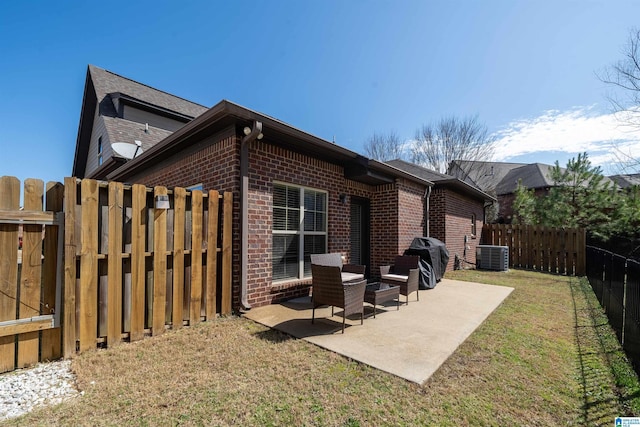 back of property featuring brick siding, a patio area, a lawn, and a fenced backyard