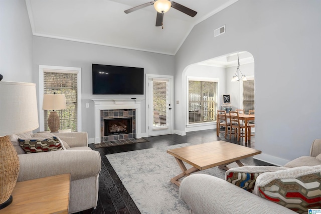 living room with lofted ceiling, wood finished floors, a tile fireplace, and ornamental molding