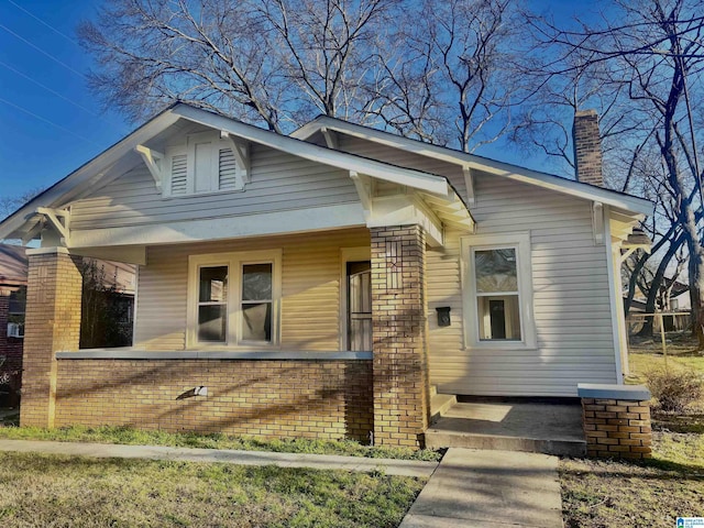 bungalow-style home featuring brick siding and a chimney