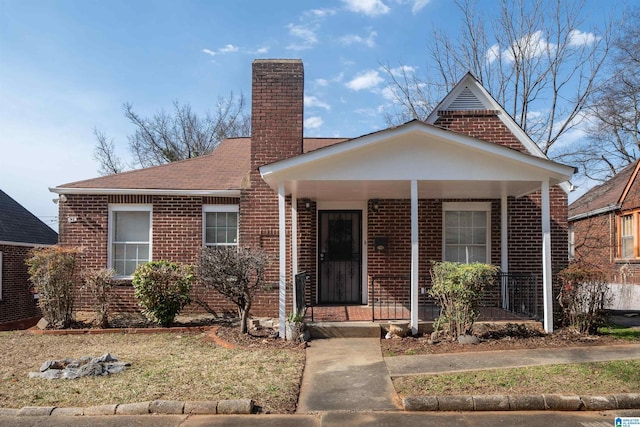 bungalow-style home with brick siding, a porch, a chimney, and roof with shingles