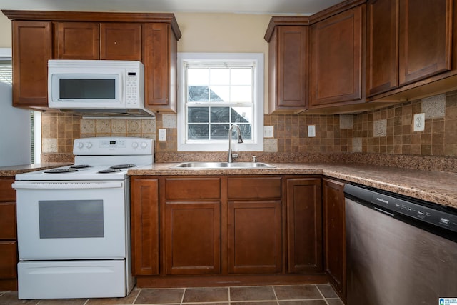 kitchen featuring decorative backsplash, brown cabinets, white appliances, and a sink