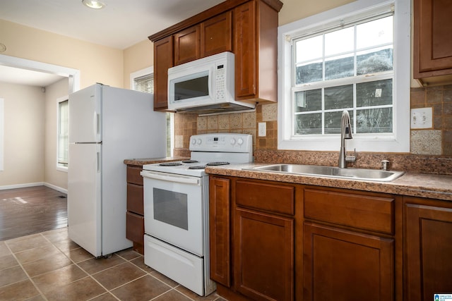 kitchen featuring white appliances, plenty of natural light, backsplash, and a sink