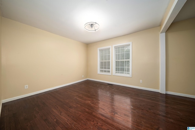 unfurnished room with visible vents, wood finished floors, and baseboards