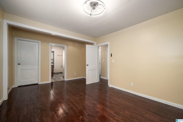 unfurnished bedroom featuring connected bathroom, baseboards, and hardwood / wood-style flooring