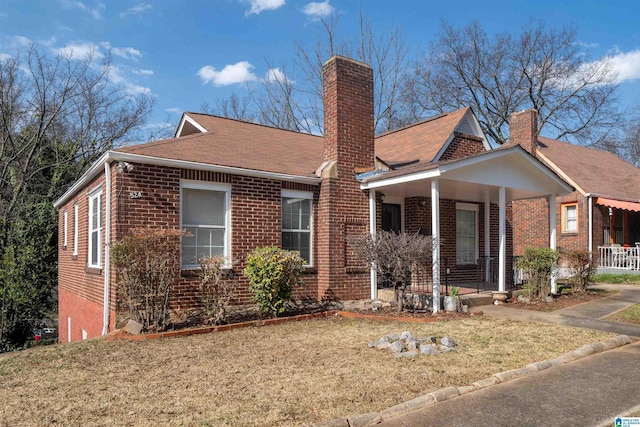 bungalow with a porch, a front lawn, brick siding, and a chimney