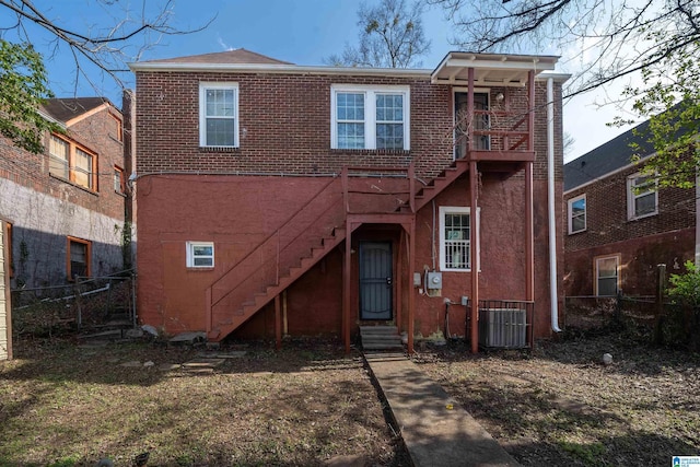 rear view of property with brick siding, fence, entry steps, stairs, and central AC unit