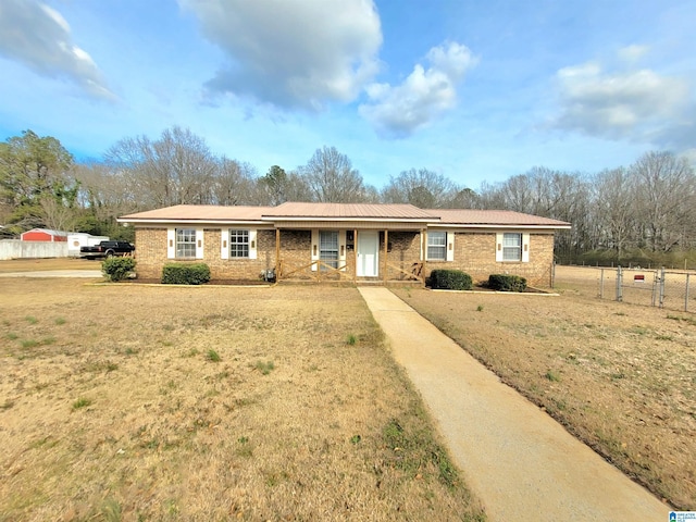 ranch-style home featuring covered porch, a front lawn, fence, and brick siding