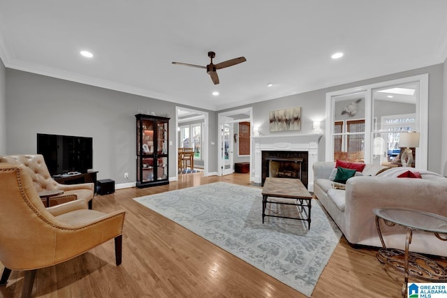 living room featuring recessed lighting, a fireplace, wood finished floors, baseboards, and crown molding