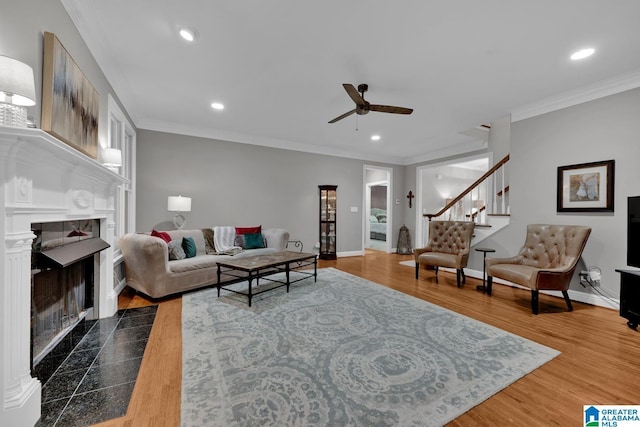 living area featuring a fireplace, ornamental molding, wood finished floors, and recessed lighting