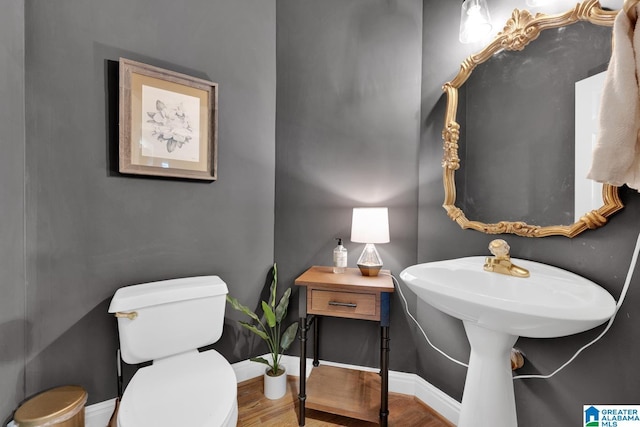 bathroom with wood finished floors, toilet, and baseboards