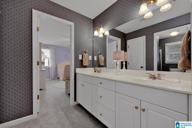 ensuite bathroom featuring baseboards, double vanity, ensuite bath, and wallpapered walls