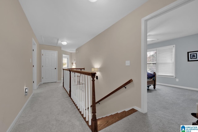 corridor featuring a wealth of natural light, carpet flooring, an upstairs landing, and baseboards