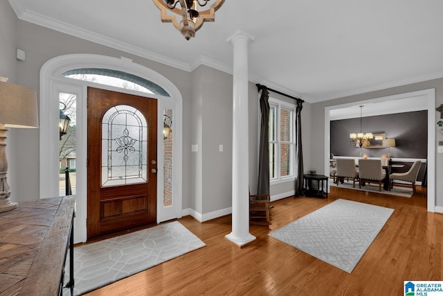 entrance foyer featuring a chandelier, plenty of natural light, ornate columns, and wood finished floors