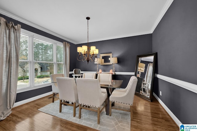 dining area with wood finished floors, crown molding, and an inviting chandelier