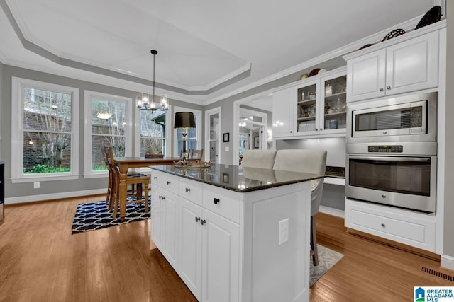 kitchen featuring stainless steel appliances, a tray ceiling, a center island, and wood finished floors