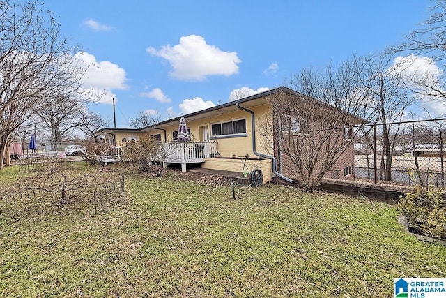 view of front of property with brick siding, a front yard, a wooden deck, and fence