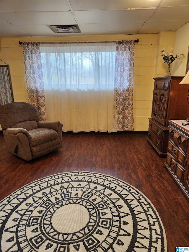 sitting room with a healthy amount of sunlight, visible vents, wood finished floors, and concrete block wall