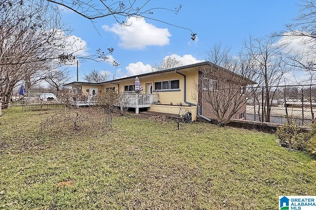 view of front of property featuring a wooden deck, fence, a front lawn, and brick siding