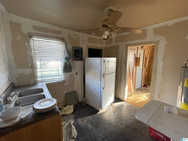 kitchen featuring a sink, water heater, a ceiling fan, and freestanding refrigerator