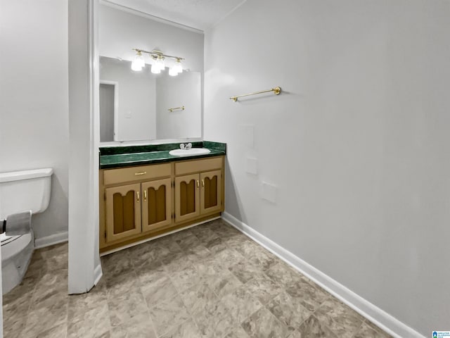 bathroom featuring baseboards, vanity, and toilet