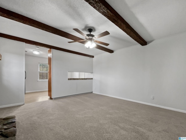 unfurnished room with a textured ceiling, light carpet, beam ceiling, and baseboards