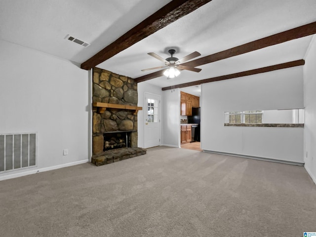 unfurnished living room featuring a stone fireplace, beam ceiling, visible vents, and baseboards