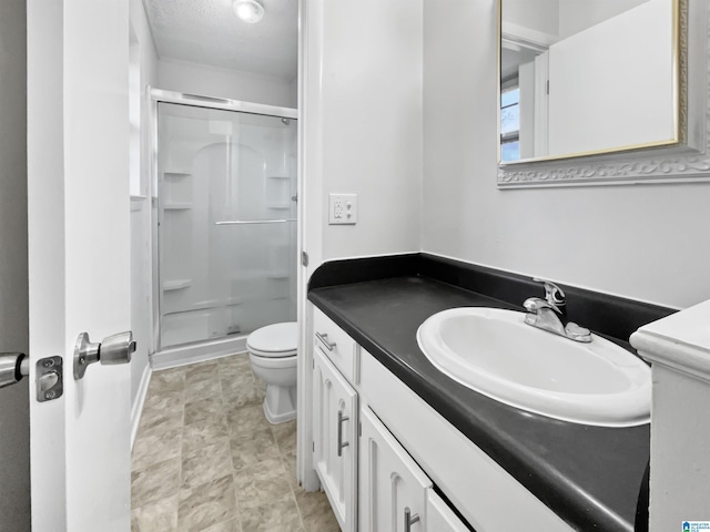 full bathroom with toilet, a stall shower, a textured ceiling, and vanity