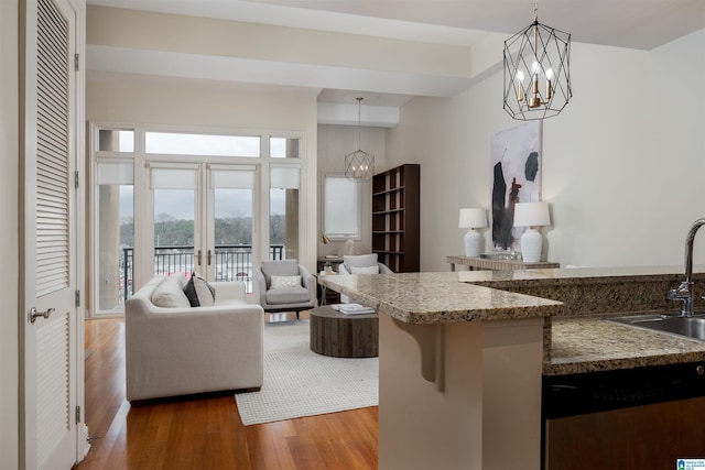 kitchen featuring a notable chandelier, open floor plan, stainless steel dishwasher, and wood finished floors